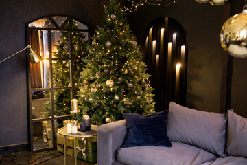 Christmas interior with a beautiful Christmas tree, sofa, light bulbs and dark background.