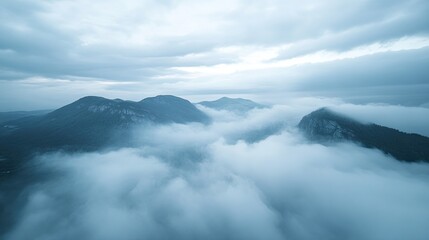 Obraz premium Aerial shot of a mountain landscape with misty clouds, open sky area for text