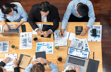 Panorama top view diverse group of business analyst team analyzing financial data report paper on meeting table. Chart and graph dashboard by business intelligence analysis. Meticulous