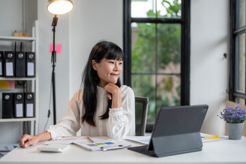 Fototapeta premium Young asian businesswoman is thinking about a new project while working at her desk
