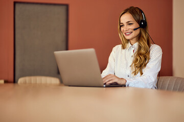 Businesswomen having an online meeting, using a laptop, and wearing headphones.