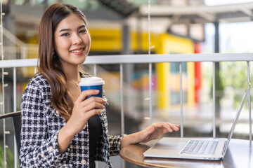 Portrait of smiling happy beautiful woman relax using technology of laptop computer sitting on chair.Young hipster creative girl freelancer business thinking with new idea content in cafe