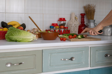 Preparation of fresh green red vegetable salad on domestic kitchen table