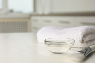 Peeling procedure. Chemical peel liquid in bowl, brush and towel on white table indoors. Space for text