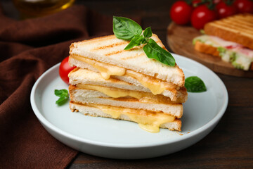 Pieces of toasted bread with melted cheese and basil on wooden table