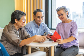Fototapeta premium Group of elderly friends sitting together and engaging with modern technology in a cozy indoor setting, senior using smartphones, connected and embracing new technology, quality of life for seniors