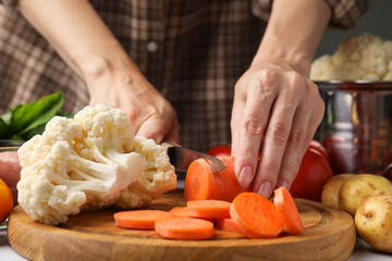 Cooking vegetable stew. Woman cutting carrot at table, closeup