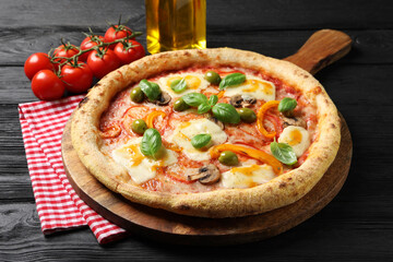 Delicious vegetarian pizza, oil and tomatoes on black wooden table