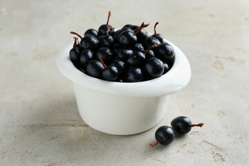 Ripe black currants in bowl on light table, closeup