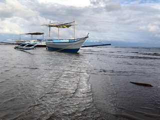Fototapeta premium Beautiful view of a boat anchored by the sea on a bright, sunny, and cloudy day.