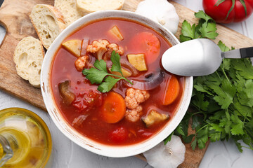 Delicious homemade stew in bowl, bread and parsley on light table, flat lay