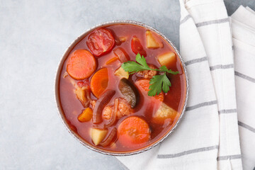 Delicious homemade stew in bowl on light table, top view