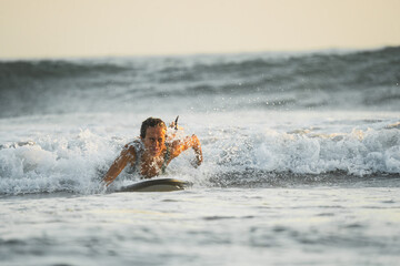 Female surfer swimming upstream to catch a wave