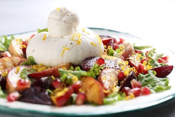 Plate with fresh burrata salad on table, closeup