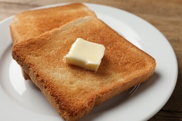 Delicious toasted bread slices with butter on table, closeup