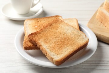 Delicious toasted bread slices on white wooden table, closeup