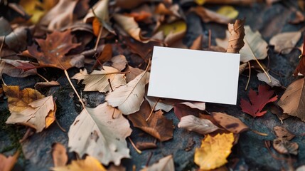 Blank white business card on autumn leaves background. Perfect for showcasing your logo or message in a seasonal setting.