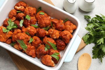 Baked cauliflower buffalo wings with parsley served on grey textured table, flat lay