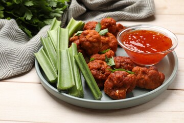 Baked cauliflower buffalo wings served on wooden table, closeup