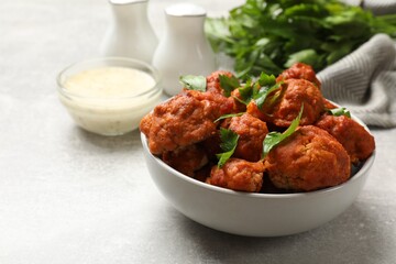 Baked cauliflower buffalo wings with parsley served on grey textured table, closeup