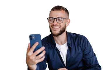 Smiling man with glasses in casual attire holding a smartphone, engaged in a video call or checking messages. Isolated on transparent background