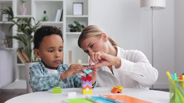 Assessment of mental development of children. Professional psychologist observes small multiracial boy playing with puzzle game, assessing his readiness for preschool. Exercises for kid with autism.