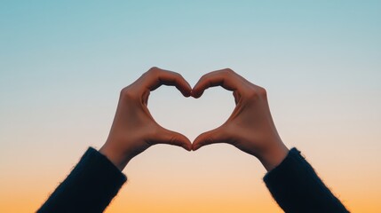 Fototapeta premium Hands Forming Heart Shape Against Sunset Sky..
