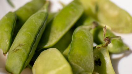 A bunch of green peas are on a white plate