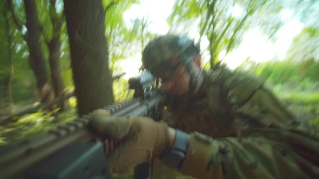 Man in protective camouflage uniform with weapons walking in the sunlight forest. The military sniper in the helmet is attacking and assaulting the enemy.