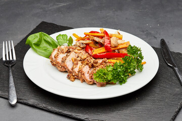 Tender sliced meat with roasted vegetables and fresh herbs on a white plate