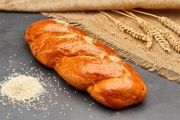 Freshly baked braided bread with sesame seeds on rustic background, ideal for bakery food projects