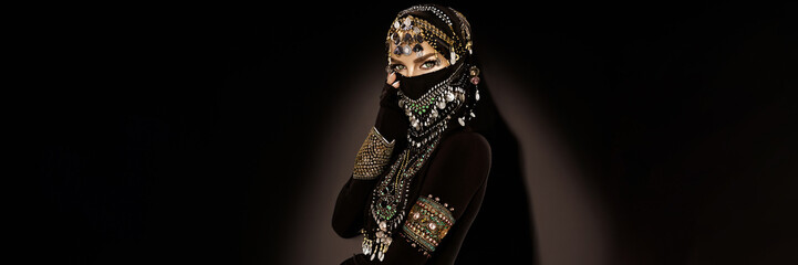 Portrait of an Arabian Princess. Beautiful Arabian woman portrait on black background. Young Hindu woman. Portrait of beauty Indian model who hiding her face behind the veil