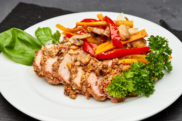 Tender sliced meat with roasted vegetables and fresh herbs on a white plate