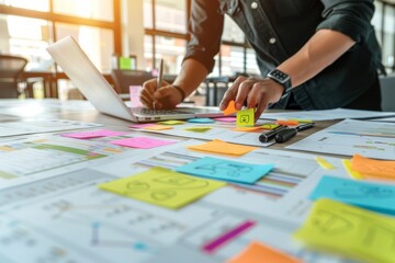 Businessman Organizing Project Ideas with Colorful Sticky Notes and Laptop on White Table.