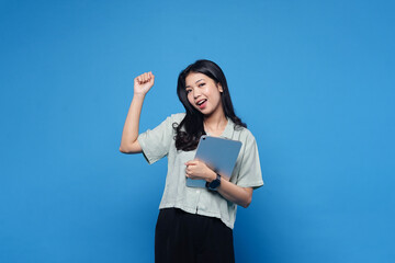 Happy success asian women holding Ipad isolated on blue background
