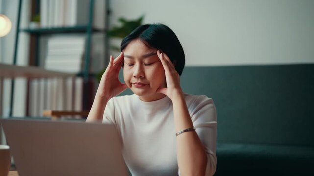 Woman in a modern office getting increasingly frustrated while working on a laptop, eventually holding her head in exasperation