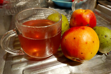 Glass Mug Filled With Warm Apple and Pear Fruit Compote to Fresh Apples and Pears in a Cozy Kitchen