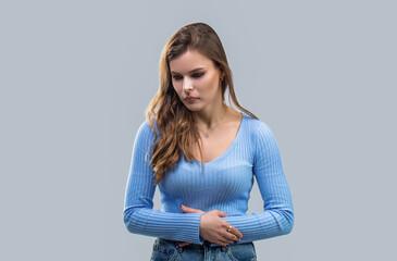 Girl with stomach ache on gray background. Woman holding stomach with both hands, the concept...
