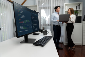 Running on coding programming intelligence system on computer screen with blurry IT developers standing with laptop at corner modern office, talking online software development information. Infobahn.