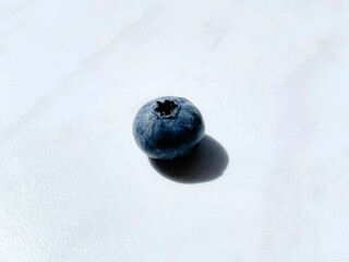 One blueberry lies on a white table