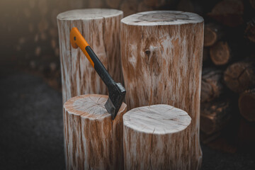 Axe cut in the chopping block in log trunks pile background. Lumber jacks wood cutting work tool.