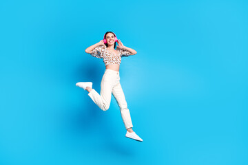 Fototapeta premium Full body portrait of nice young lady headphones jump wear top isolated on blue color background