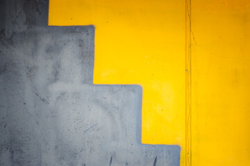 A yellow wall with a gray staircase painted on it