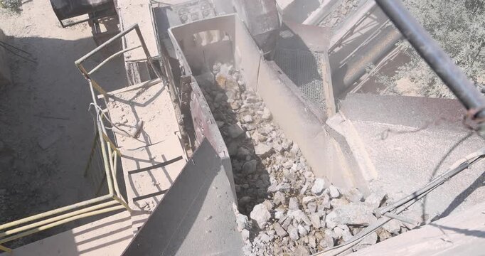 Stone crushing machine at open pit mining and processing plant for crushed stone. Loading of stone into the crusher and conveyor belts. Industry of building materials sand and gravel