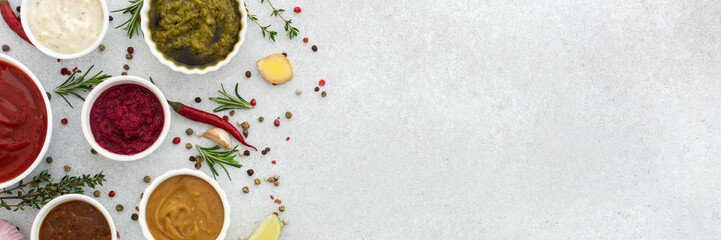 Different types of sauces in bowls with seasonings banner, rosemary and pepper, thyme and garlic, lime and lemon, cilantro, top view, copy space