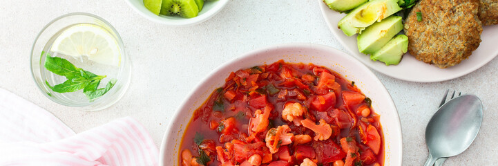 Red soup with beet, beans and vegetables and cauliflower, chickpea cutlets and mixed salad with avocado, delicious hearty breakfasts or lunches, top view of a set table with food, banner