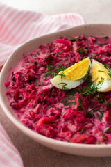 Summer cold beetroot soup made from beets, radishes, cucumbers, potatoes and herbs, garnished with egg, a refreshing summer lunch