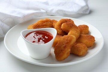Tasty chicken nuggets with chili sauce on white table, closeup