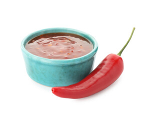 Hot chili sauce in bowl and pepper isolated on white