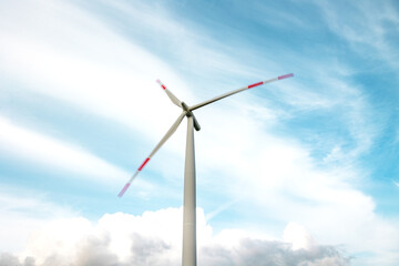 Wind turbine with rotating blades, clouds in the background. The ends of the blades are blurred.